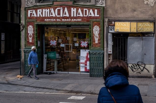 Una mujer porta una mascarilla mientras pasea a su perro frente a una farmacia en el centro de Barcelona, España, el 18 de marzo de 2020. (Xinhua/Joan Gosa).