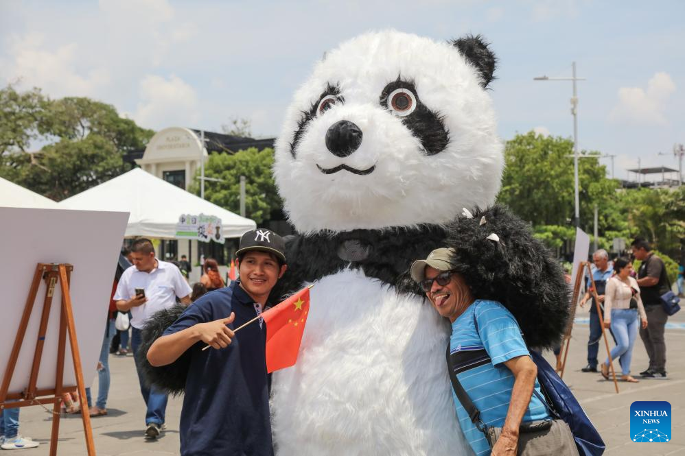 Imagen del 25 de abril de 2025 de hombres abrazando a una persona disfrazada de oso panda durante la celebración del Día Internacional del Idioma Chino en la Plaza Gerardo Barrios, en la ciudad de San Salvador, capital de El Salvador. Estudiantes del Instituto Confucio de la Universidad de El Salvador y personas interesadas en la civilización china celebraron el viernes el Día Internacional del Idioma Chino con una serie de actividades llenas de encanto y tradición. (Xinhua/Alexander Peña)