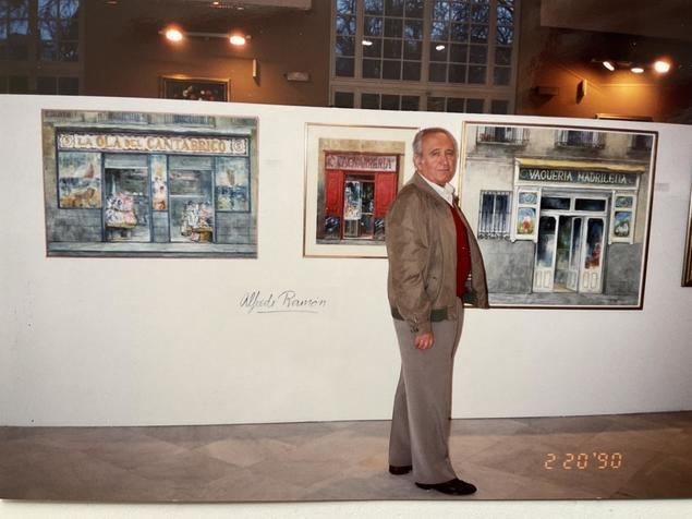 El pintor Alfredo Ramón delante de tres sus cuadros, en el que retrata fachadas de paisajes madrileños de los años 60 y 70 del siglo XX. Fotografía de Linda Hament.
